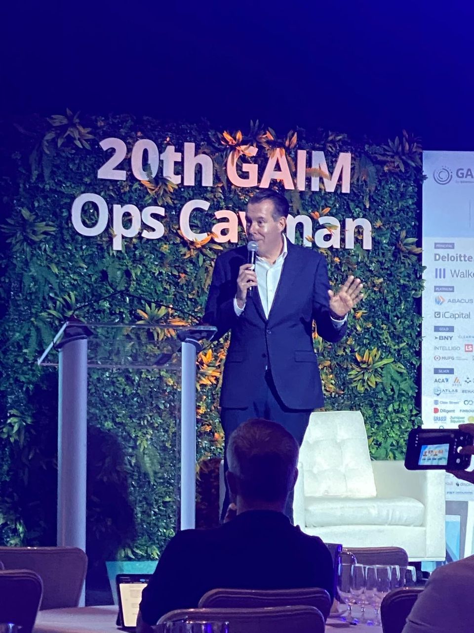 Speaker with a microphone on stage at the 20th GAIM Ops Cayman conference